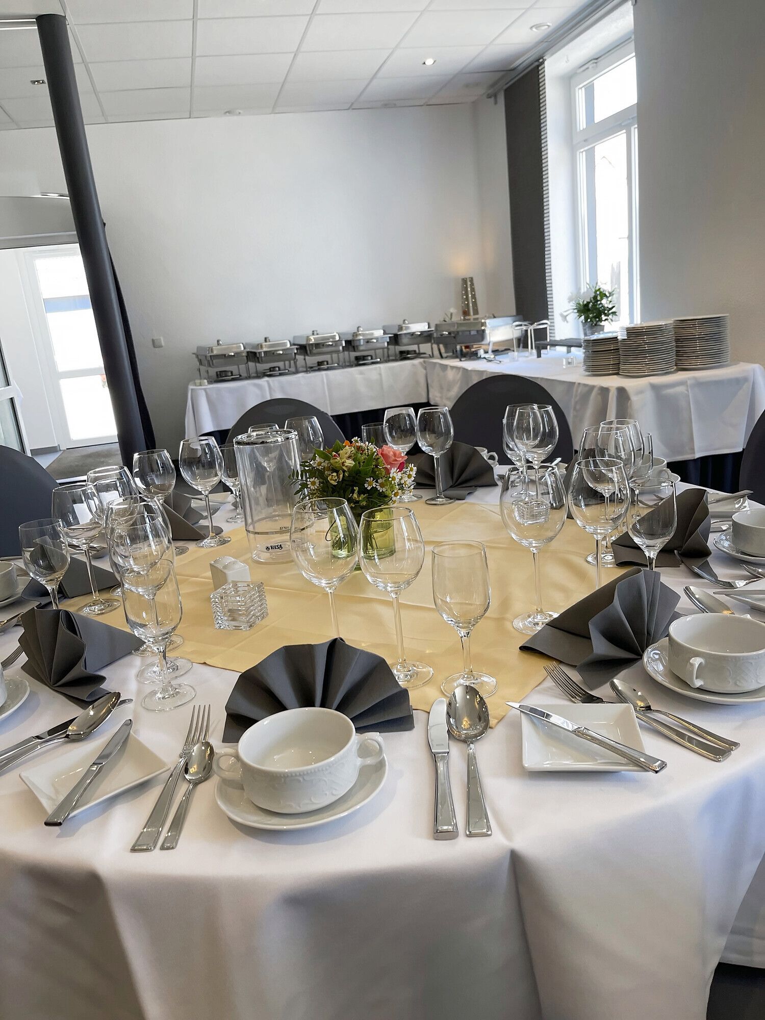Eingedeckter Tisch in der Blaupause, im Hintergrund das Buffet