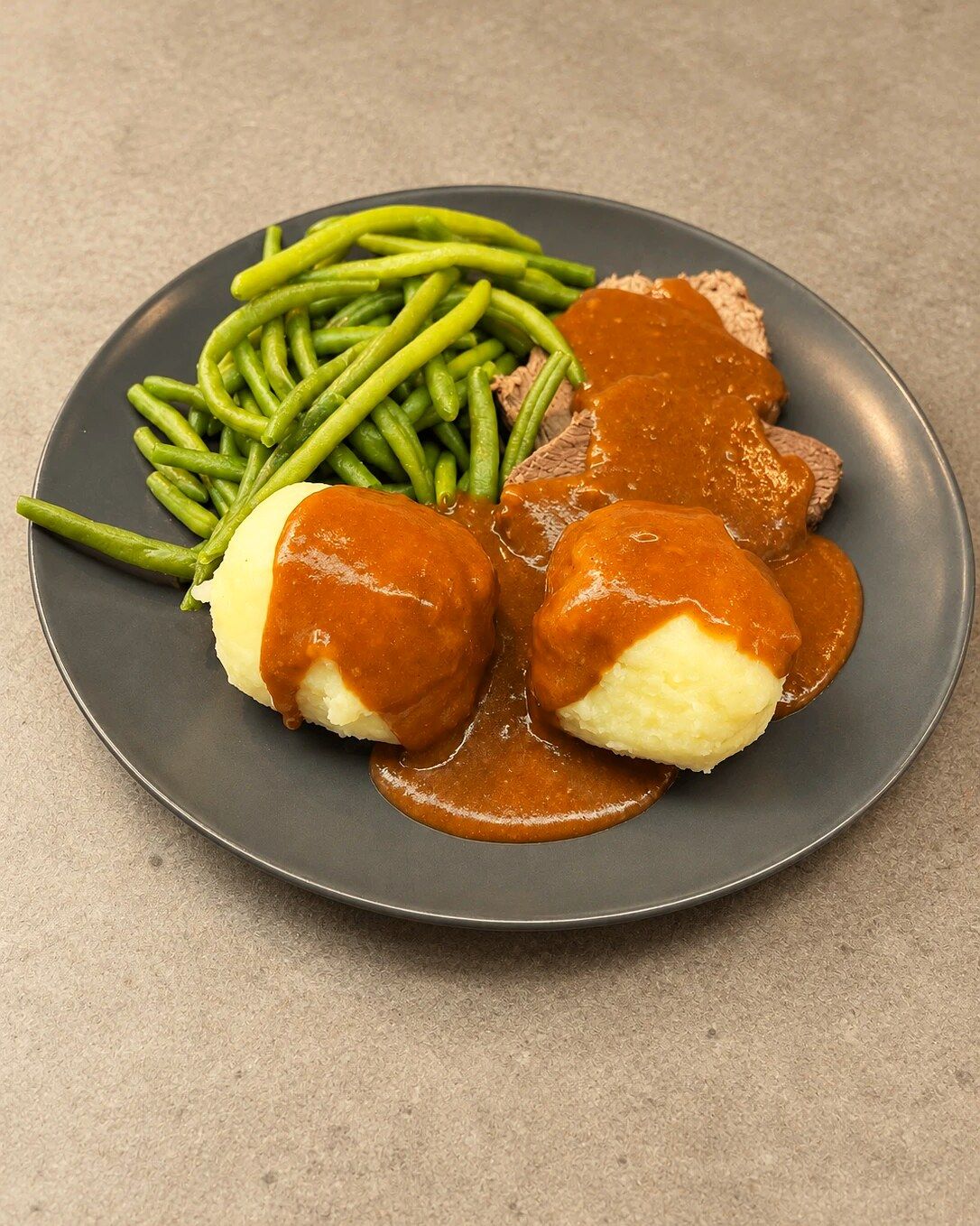 Rinderbraten mit Kartoffelpüree, Soße und grünen Bohnen auf dem Teller